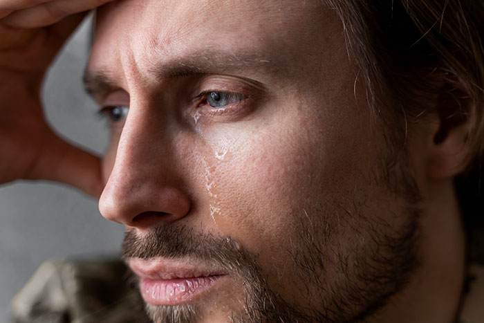 Close-up of a man with tears on his face, looking distressed after learning about his fiancée's love for her friend. Close-up of a man with tears on his face, looking distressed after learning about his fiancée's love for her friend.