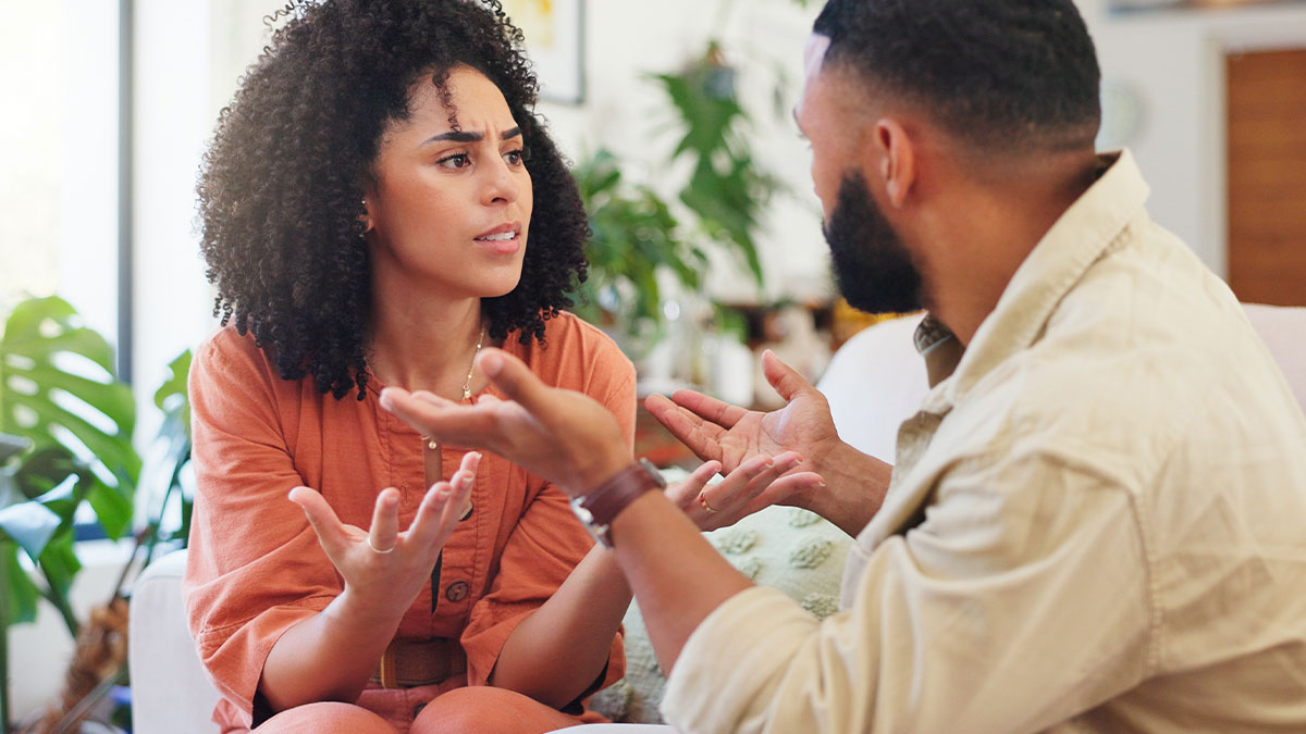 Woman and man having a serious conversation indoors, reflecting tension about vacation and autistic child issues.