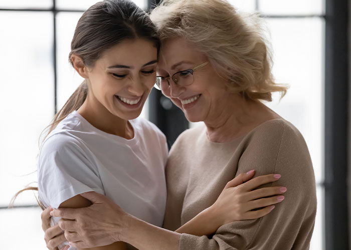 Mom hugging daughter, smiling warmly in a bright room, capturing complex feelings of favorite child and family dynamics. Mom hugging daughter, smiling warmly in a bright room, capturing complex feelings of favorite child and family dynamics.
