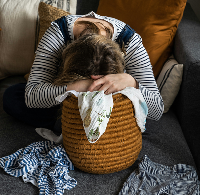 Young woman with head down on woven basket near scattered clothes illustrating clean f***k mom daughter clothes drawers stress. Young woman with head down on woven basket near scattered clothes illustrating clean f***k mom daughter clothes drawers stress.