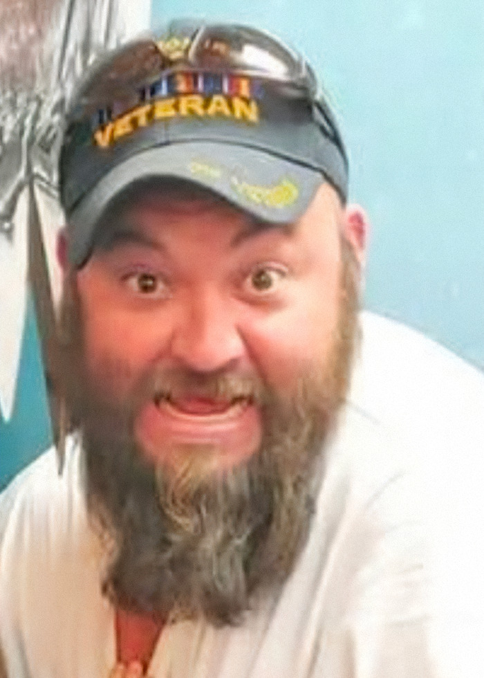 Bearded man wearing a veteran cap with sunglasses, expressing a surprised or intense emotion indoors. Bearded man wearing a veteran cap with sunglasses, expressing a surprised or intense emotion indoors.