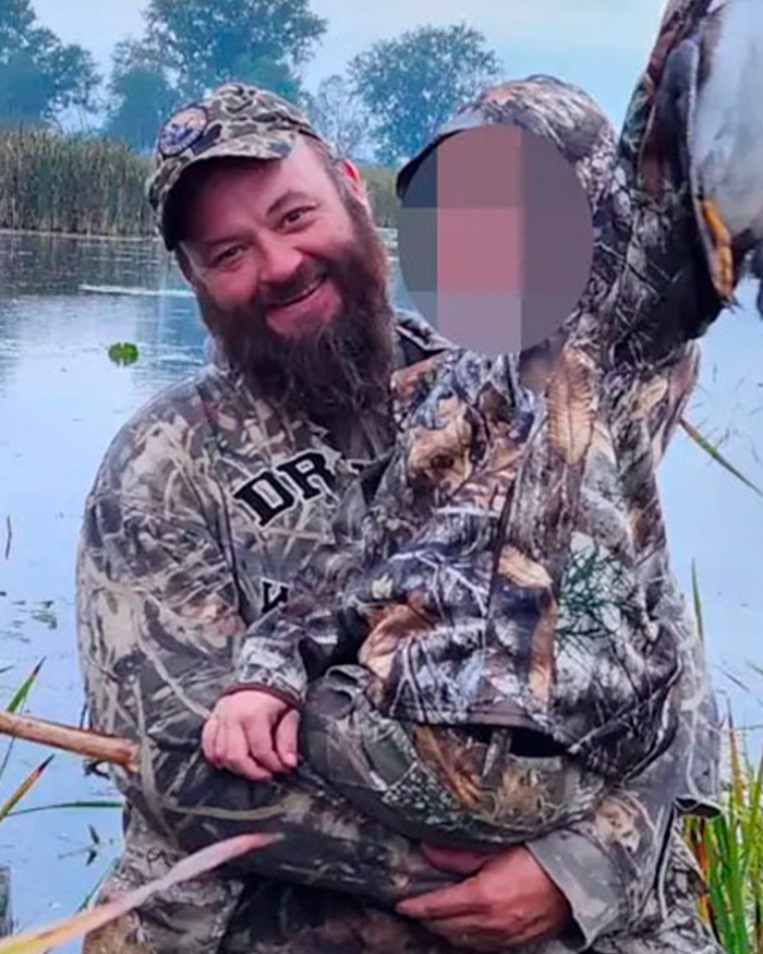 Man in camouflage holding child with blurred face near water, related to Mormons raising funds for Michigan church attacker. Man in camouflage holding child with blurred face near water, related to Mormons raising funds for Michigan church attacker.