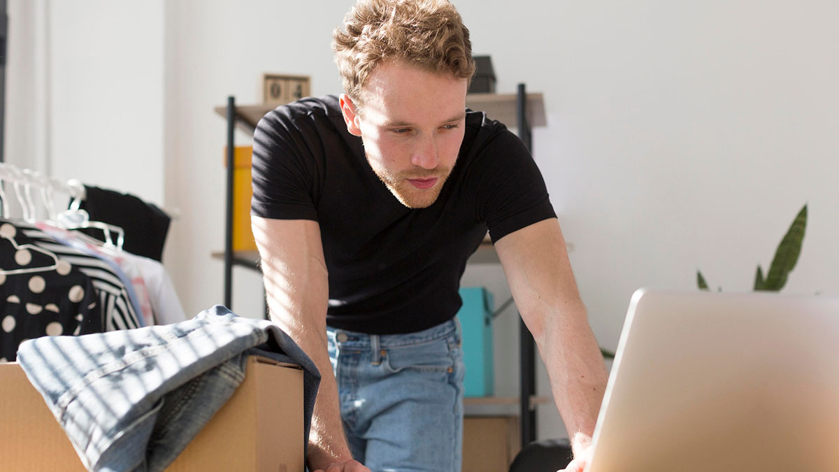 Man researching zip-line your boxes out moving advice online while packing boxes at home