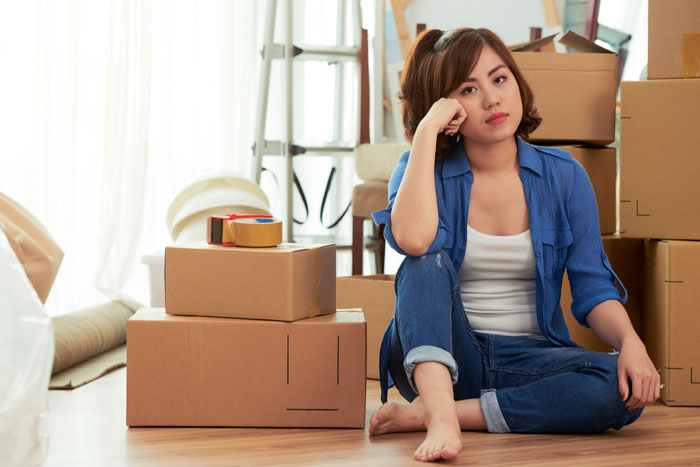 Young woman vents frustration about useless bro, sitting among moving boxes in a casual blue shirt and jeans. Young woman vents frustration about useless bro, sitting among moving boxes in a casual blue shirt and jeans.