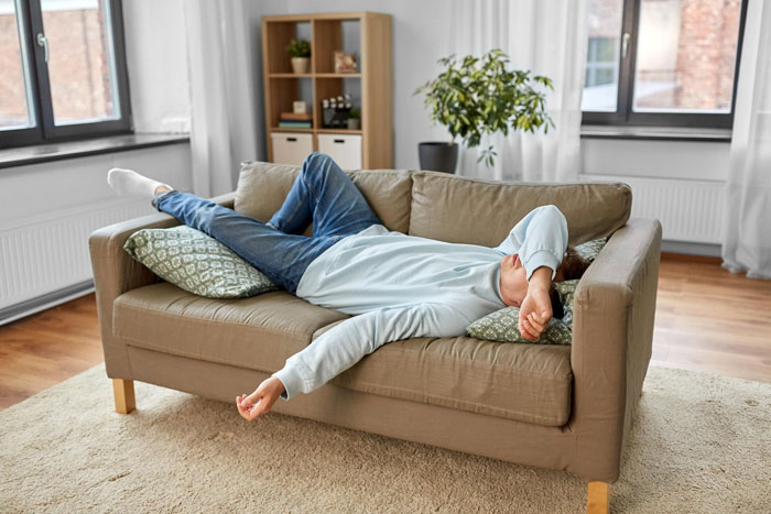 Young man lying on couch looking frustrated and exhausted, illustrating useless bro feeling in a modern living room. Young man lying on couch looking frustrated and exhausted, illustrating useless bro feeling in a modern living room.