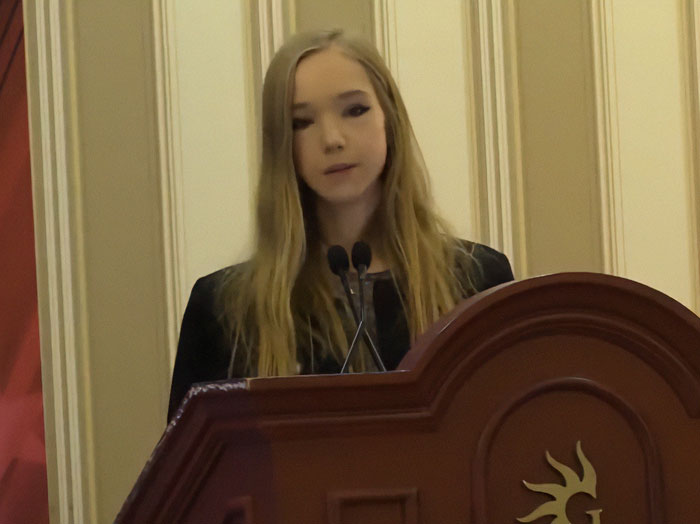 German activist known as Anti Greta speaking at a podium during a formal event, seeking asylum in the US.