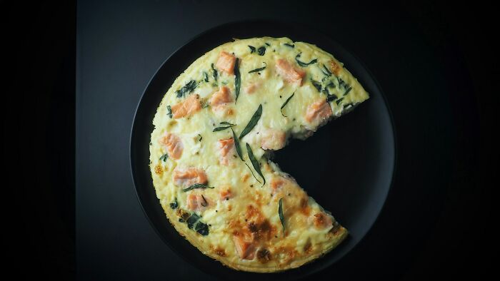 Creamy shrimp jello dish served on a black plate with herbs and chunks of shrimp visible on top.