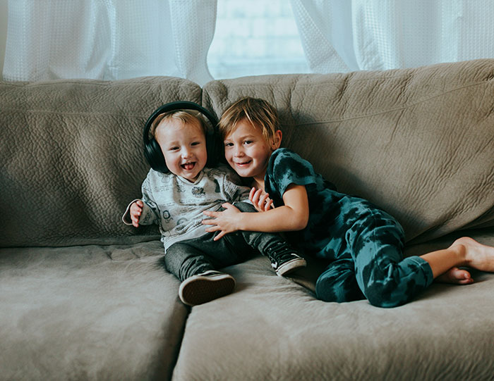 Two young kids sitting and playing on a couch, highlighting sibling care and family dynamics after mom abandonment. Two young kids sitting and playing on a couch, highlighting sibling care and family dynamics after mom abandonment.