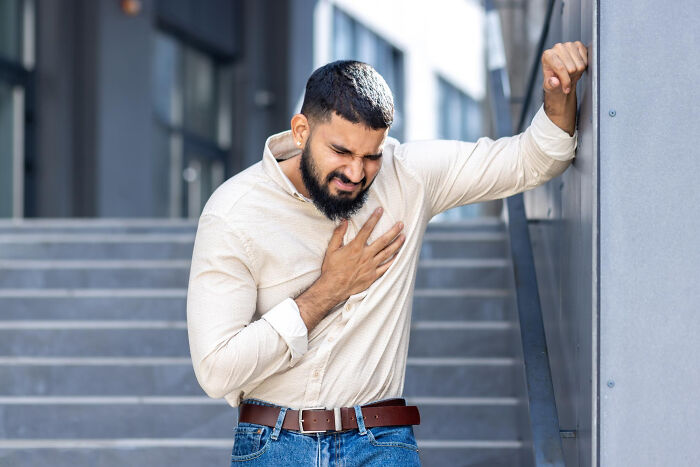 Man clutching chest in pain outside building, illustrating moments patients swore everything was fine but doctors knew otherwise.
