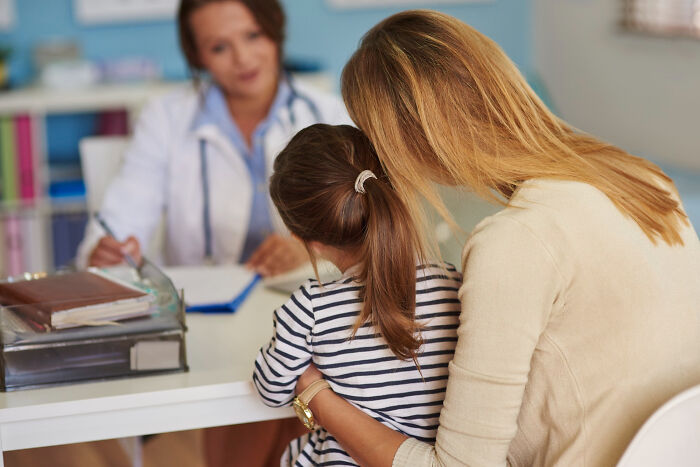 Mother and child in a medical office as doctor identifies moments patients swore everything was fine but something wasn’t right