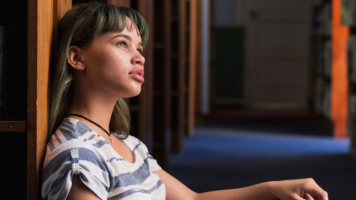 Young woman leaning against a bookshelf, looking worried, illustrating patients brushing off terrifying symptoms as normal.