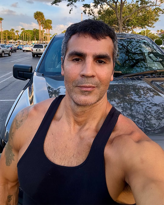 Man in a black tank top taking a selfie outdoors by a parked car, related to Jennifer Lopez's ex-husband cheating accusation. Man in a black tank top taking a selfie outdoors by a parked car, related to Jennifer Lopez's ex-husband cheating accusation.