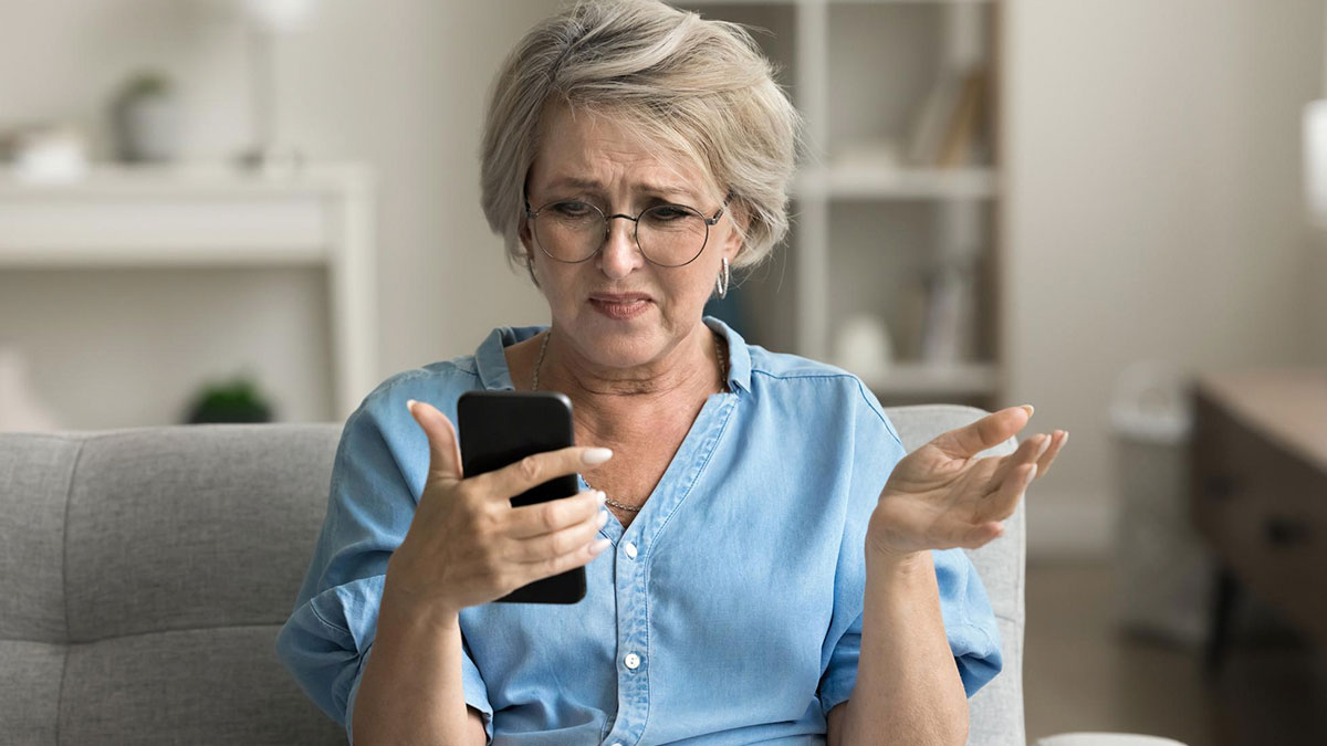 Older woman wearing glasses looking confused at smartphone showing tech fails from parents in a home setting