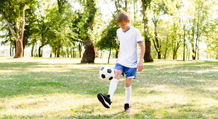 Young boy in sportswear playing soccer alone in a sunlit park, representing themes of toxic parents and family dynamics. Young boy in sportswear playing soccer alone in a sunlit park, representing themes of toxic parents and family dynamics.