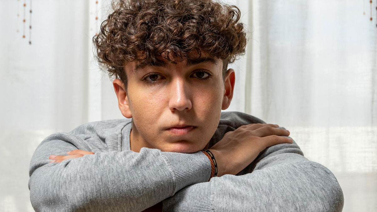 Young man with curly hair looking sad and reflective, depicting the impact of toxic parents and sibling favoritism.