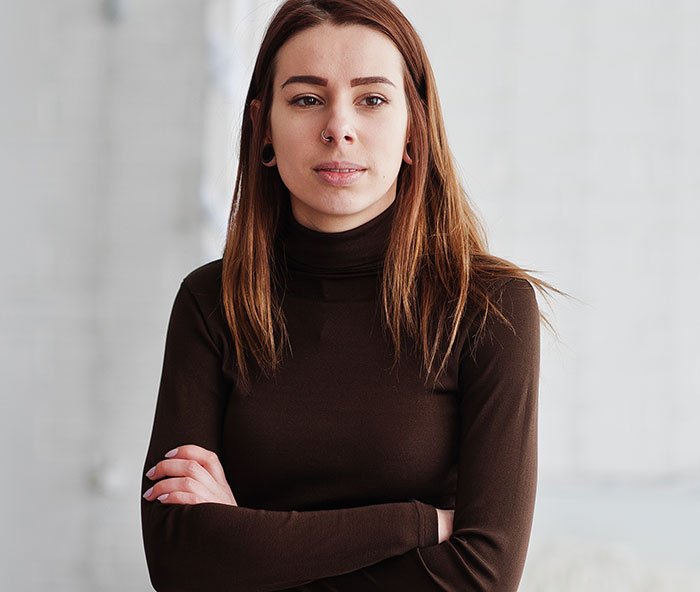 Young woman with serious expression and crossed arms, setting a boundary about disabled brother’s care. Young woman with serious expression and crossed arms, setting a boundary about disabled brother’s care.