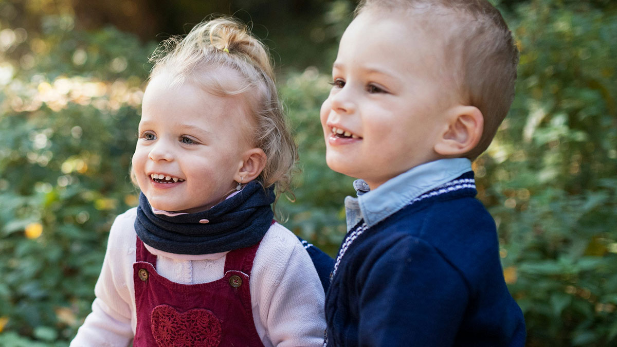 Two young children smiling outdoors during a playful moment at a memorable disastrous playdate for parents.