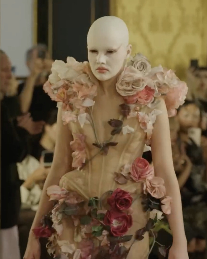 Model with white face paint wearing floral avant-garde dress at a boundary-breaking Paris Fashion Week show inspired by Hunger Games. Model with white face paint wearing floral avant-garde dress at a boundary-breaking Paris Fashion Week show inspired by Hunger Games.