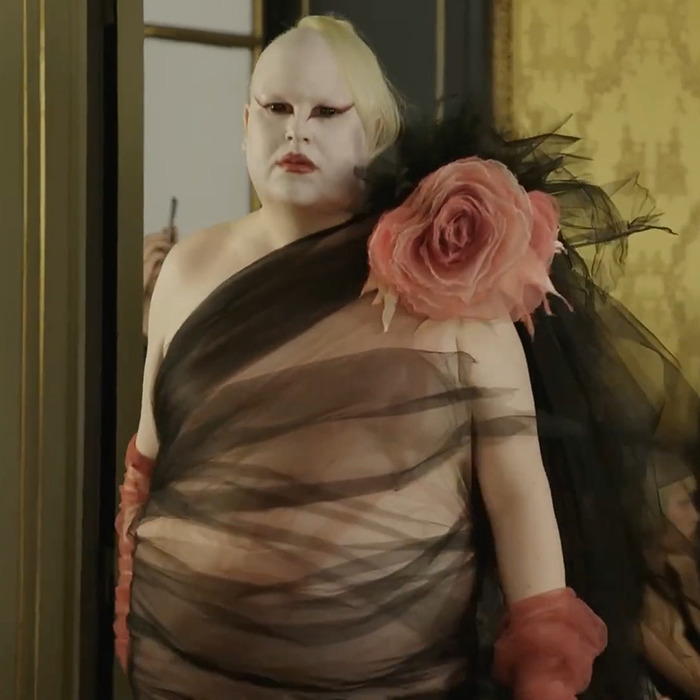 Model wearing avant-garde sheer black fabric with large pink flower at Paris Fashion Week stirring Hunger Games buzz. Model wearing avant-garde sheer black fabric with large pink flower at Paris Fashion Week stirring Hunger Games buzz.