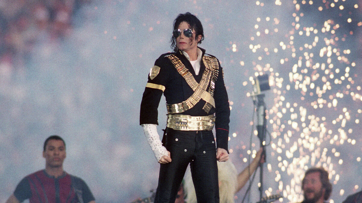 Michael Jackson performing on stage with pyrotechnics in the background during a live concert event.