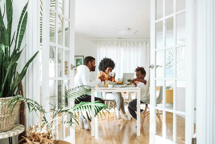 A family sharing a meal at a bright dining table, reflecting on childhood moments they still cringe about today.