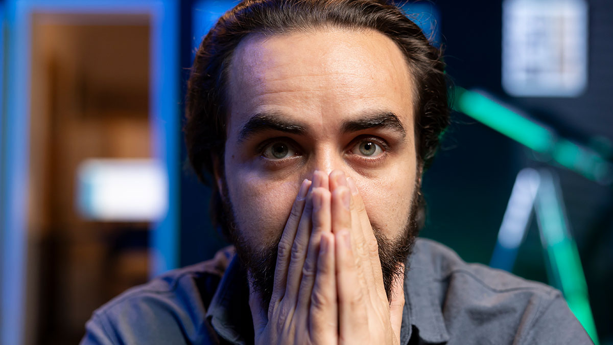 Man with intense expression covering mouth with hands, conveying urgency in wild we need to leave right now stories.