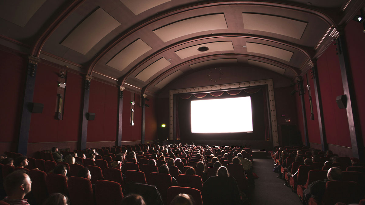 Audience watching a movie in a dark vintage cinema theater, evoking nightmare situations people survived.