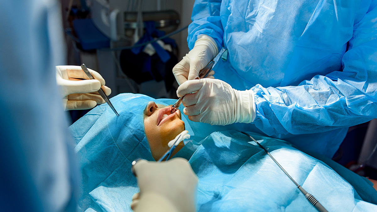 Surgeons operating on a patient under anesthesia in a sterile environment during a surgical procedure.