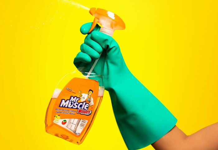 Hand in green glove holding a bottle of cleaning spray, illustrating strange and dumb health hacks shared by patients.