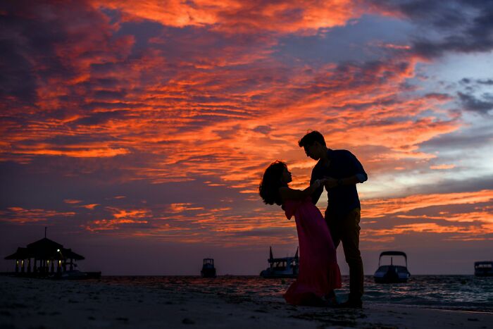 Couple dancing on a beach at sunset with a dramatic sky, evoking eerie and disturbing vibes for creepy moments.