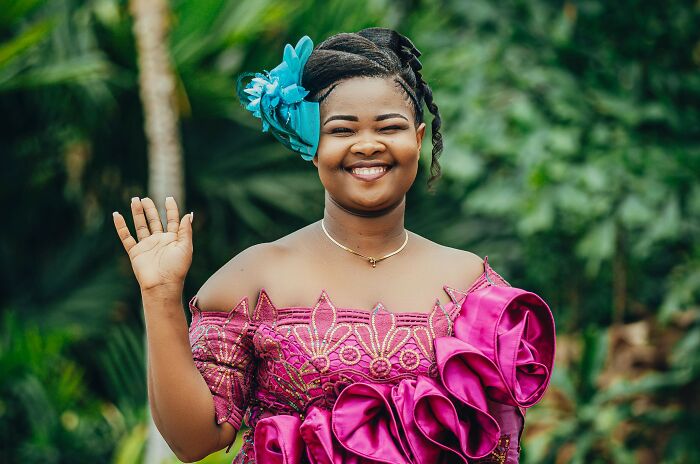 Smiling woman in vibrant traditional dress waving hand outdoors, representing foreign greetings and farewells for language geniuses. Smiling woman in vibrant traditional dress waving hand outdoors, representing foreign greetings and farewells for language geniuses.