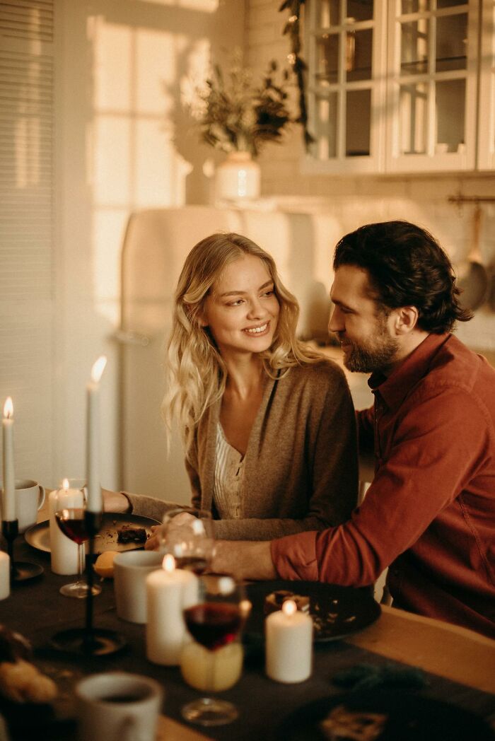 Couple sharing an intimate moment at candlelit dinner, illustrating first signs someone is having an affair concept.