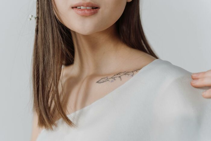 Close-up of a woman showing a delicate tattoo on her collarbone, illustrating tattoo artists refused to ink on people.