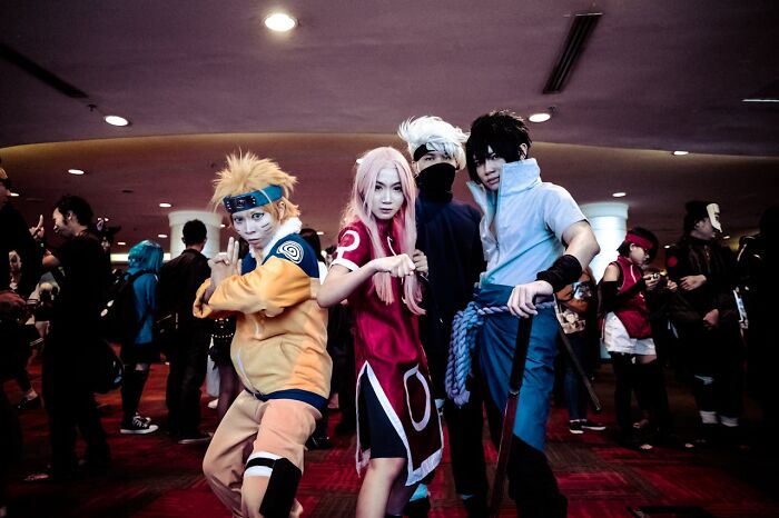 Group of cosplayers posing in detailed costumes at a crowded event, capturing the creepy and disturbing vibe of fandom culture.