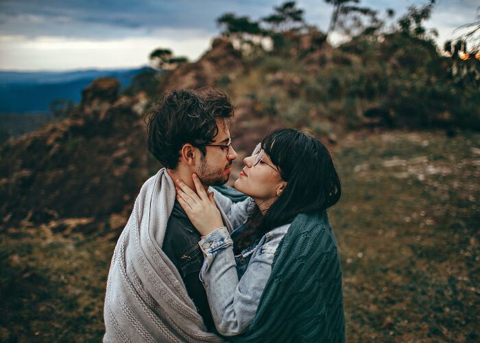 Couple wrapped in blankets embracing outdoors at sunset, evoking feelings of intimacy amid highly disturbing creepy moments.