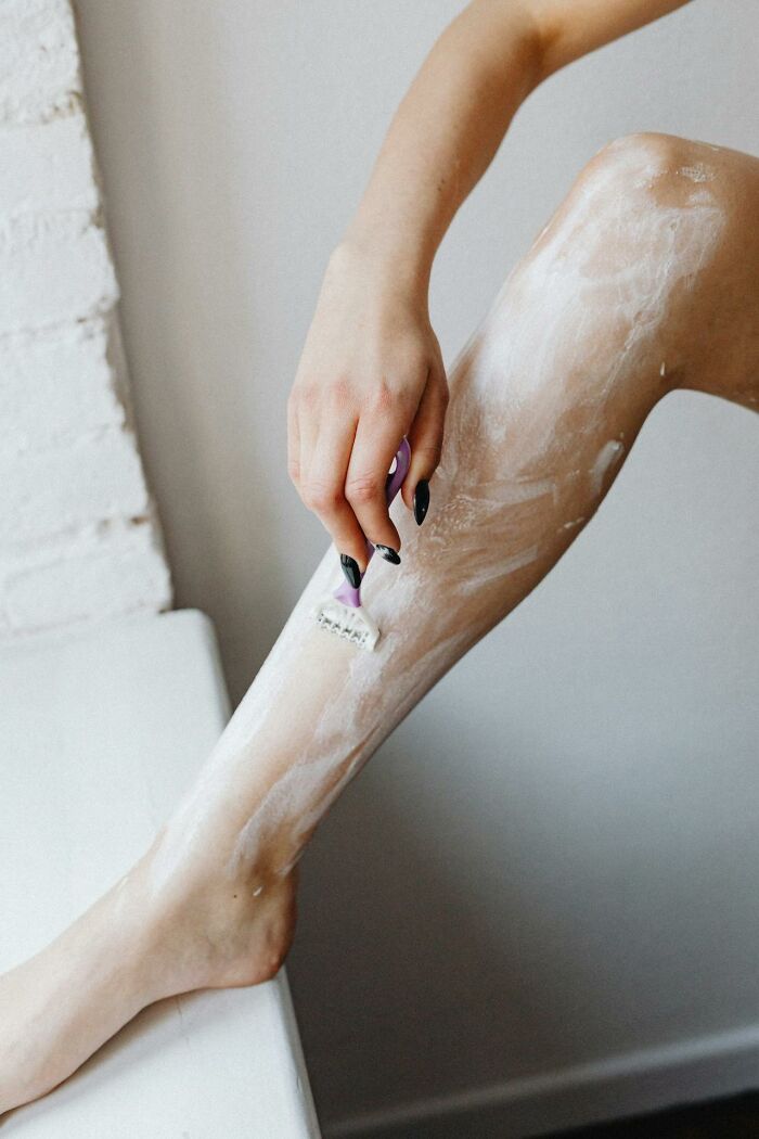 Person shaving leg with razor, illustrating signs that scream someone is having an affair concept.