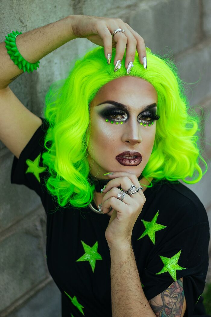 Person with neon green hair and bold makeup posing, showcasing bizarre style found inside strangers' houses.