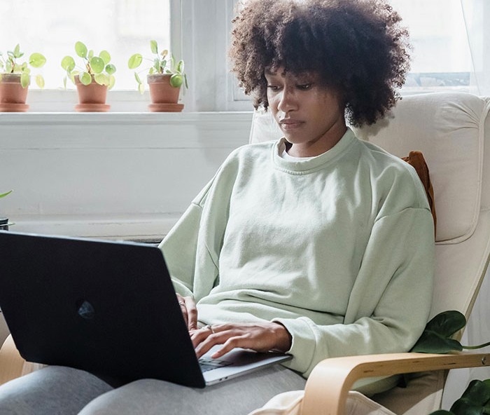 Young woman using laptop at home, reflecting on financial favor and loan decisions in a quiet living room setting. Young woman using laptop at home, reflecting on financial favor and loan decisions in a quiet living room setting.