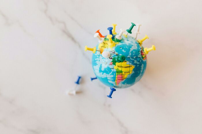 Small globe with colorful push pins marking various locations, illustrating a global geography challenge concept. Small globe with colorful push pins marking various locations, illustrating a global geography challenge concept.