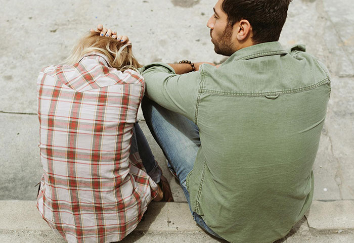 Woman sitting with head down beside man, depicting suspicion and emotional distress after months of mysterious illness. Woman sitting with head down beside man, depicting suspicion and emotional distress after months of mysterious illness.