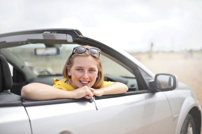 Young woman smiling in a convertible car holding keys, a scene unrelated to highly disturbing things folks found creepy later.
