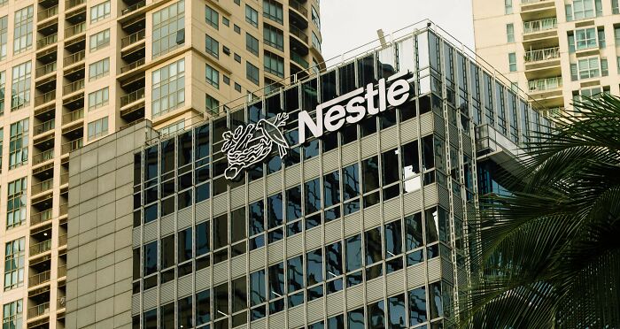 Modern office building with Nestle logo on glass facade, symbolizing corporate environment and long grudges held.
