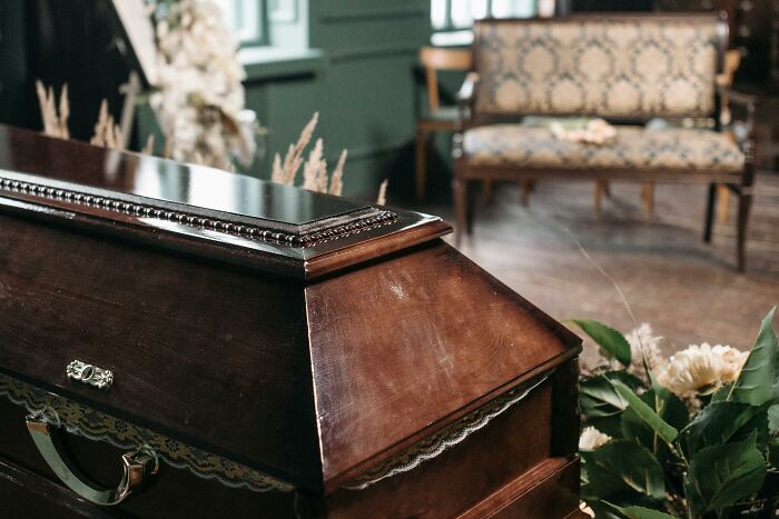 A unique college course in mortuary science with a wooden coffin and floral arrangements in a traditional setting.