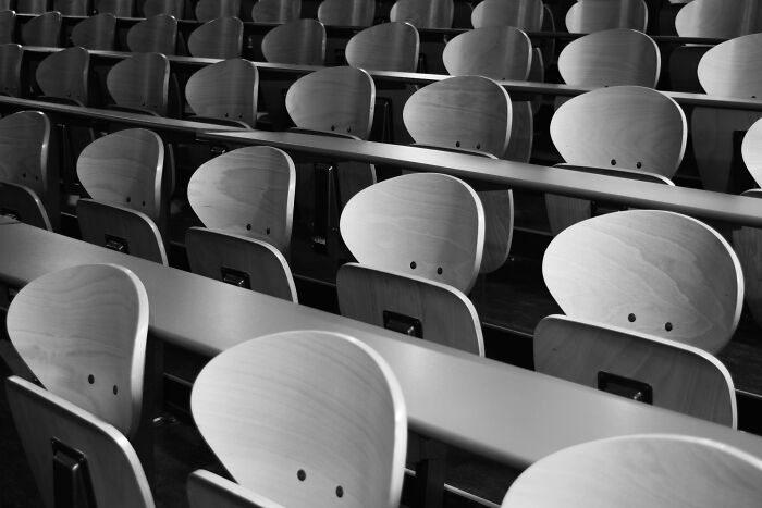 Empty classroom with rows of wooden chairs and desks representing general knowledge test setting for 6th grader quiz. Empty classroom with rows of wooden chairs and desks representing general knowledge test setting for 6th grader quiz.