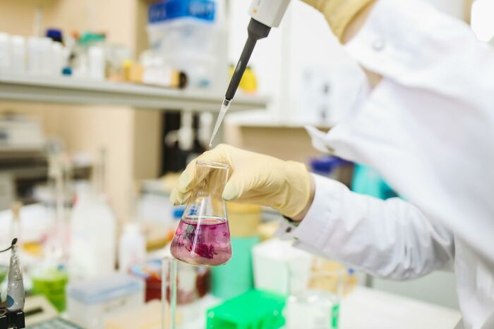 Scientist in lab gloves handling chemicals with a pipette, illustrating people share potentially dangerous situations in labs.
