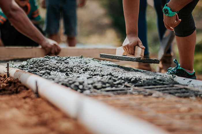 Close-up of hands smoothing wet concrete with a trowel during outdoor construction work on a sunny day. Close-up of hands smoothing wet concrete with a trowel during outdoor construction work on a sunny day.