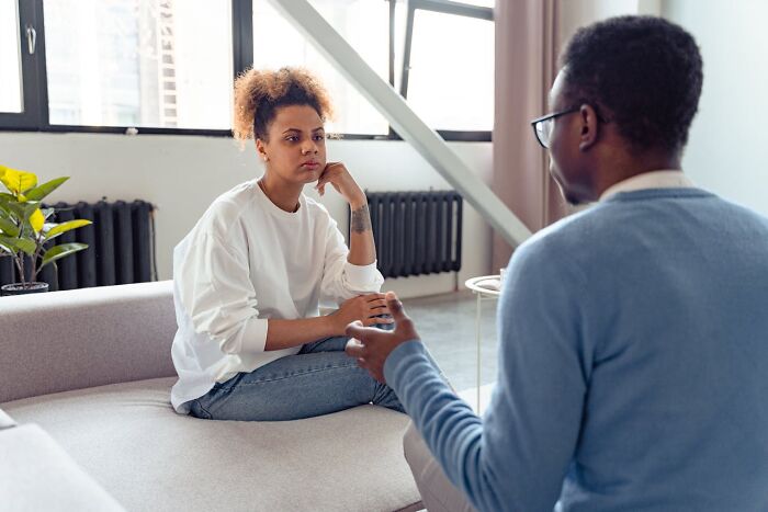 Couple having a serious conversation on sofa, reflecting on relationship issues and signs of someone having an affair.