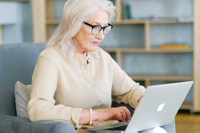 Older woman with glasses struggling with laptop, illustrating parents with bad technology skills in a humorous way.