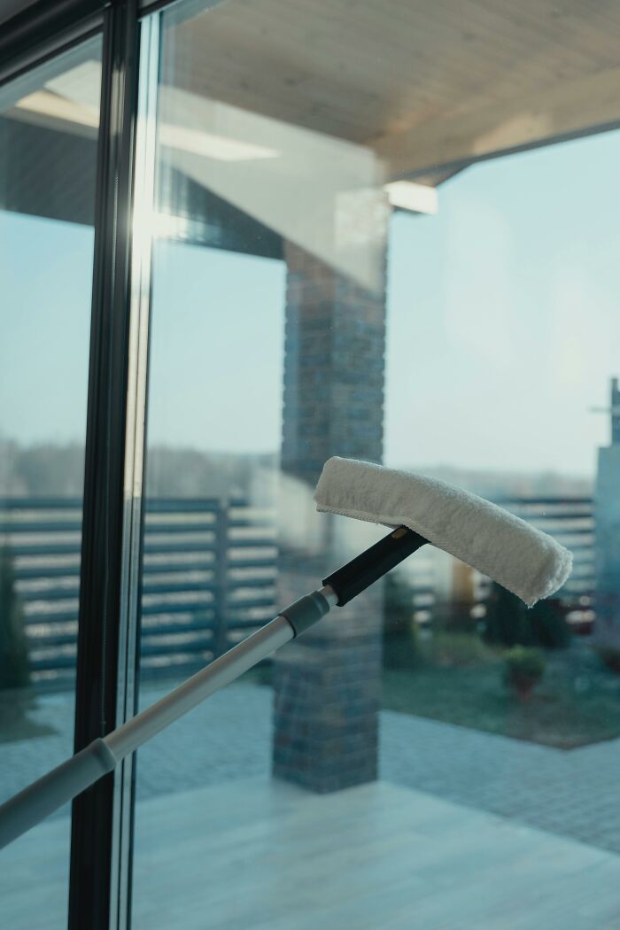 Window cleaning tool wiping a glass door, related to weird things workers have seen inside strangers’ homes.