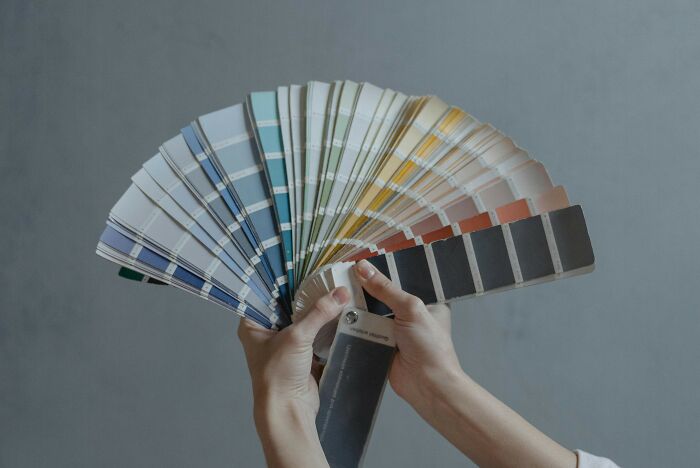 Hands holding a fan of paint swatches showing various color shades for a color missing images challenge Hands holding a fan of paint swatches showing various color shades for a color missing images challenge